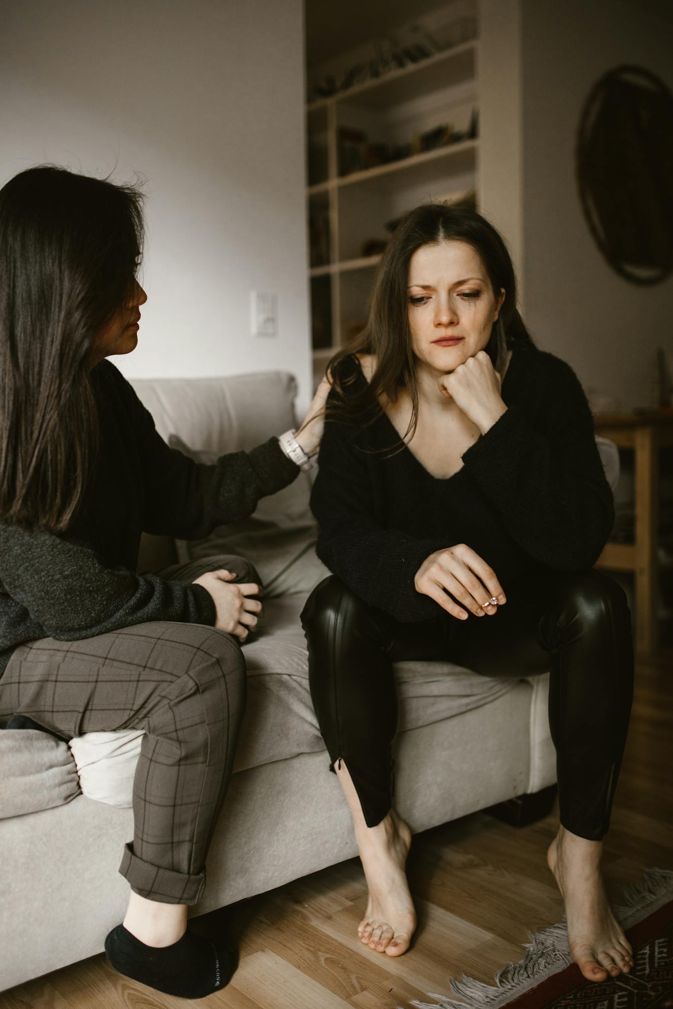 Two women sharing a moment of empathy and support in an intimate indoor setting.